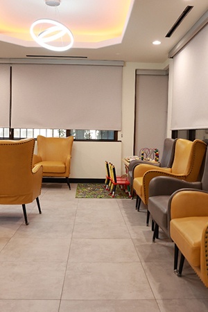 Large, comfortable waiting area in healthcare office with shades covering the windows
